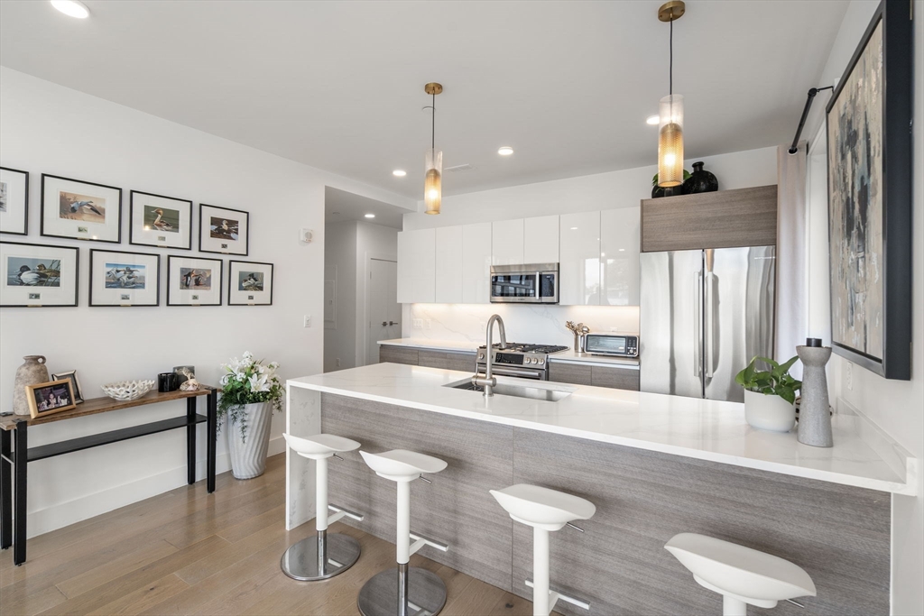 30 Penniman Road, Unit 201 Boston, MA 02134 - Photo 7 of 23 a view of kitchen island with stainless steel appliances furniture refrigerator dining table and chair