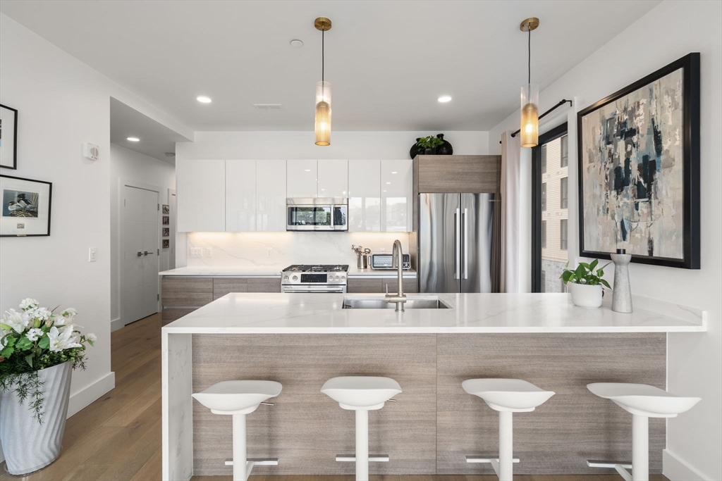 30 Penniman Road, Unit 201 Boston, MA 02134 - Photo 8 of 23 a kitchen with stainless steel appliances granite countertop a kitchen island a table and chairs in it