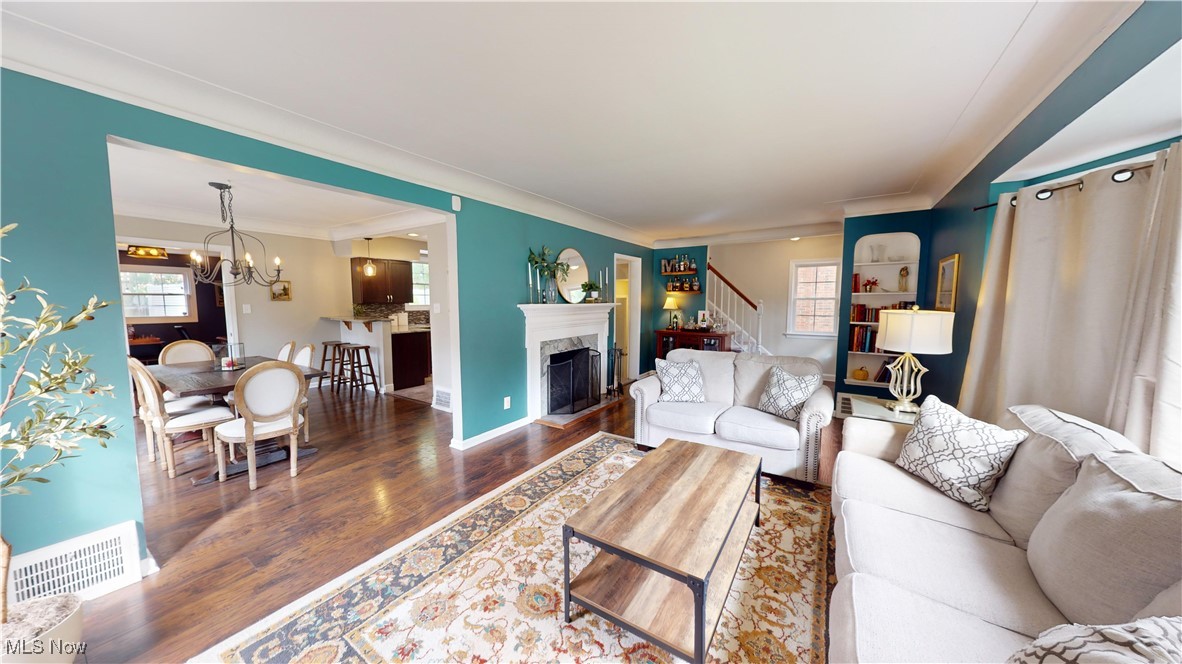 2412 Charney Road Cleveland, OH 44118 - Photo 7 of 48 Living room featuring crown molding, dark wood-type flooring, and a notable chandelier