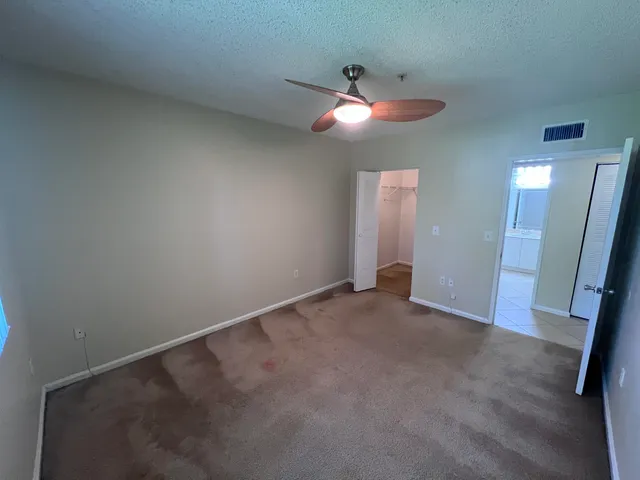 an empty room with closet and a chandelier fan
