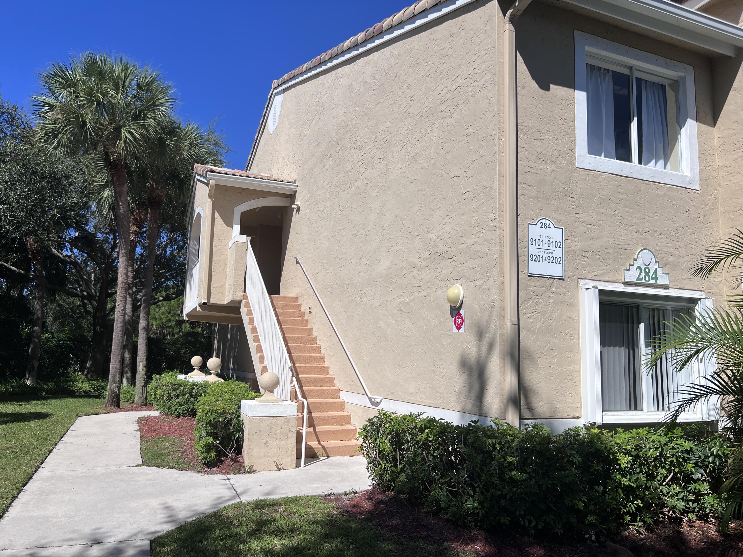 284 Village Boulevard, Unit 9202 Tequesta, FL 33469 - Photo 2 of 16 a front view of a house with a yard