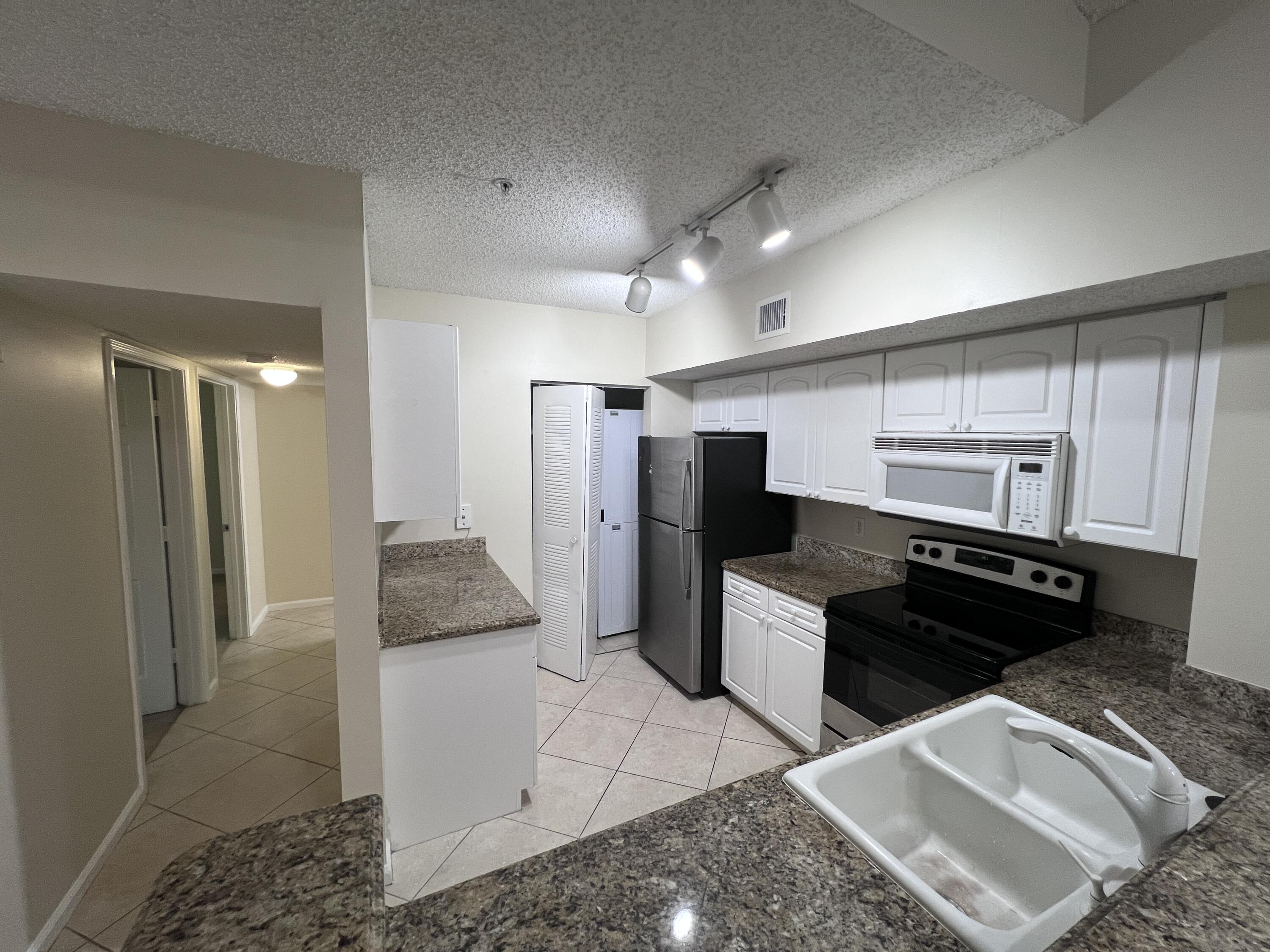 284 Village Boulevard, Unit 9202 Tequesta, FL 33469 - Photo 8 of 16 a kitchen with a refrigerator and a sink