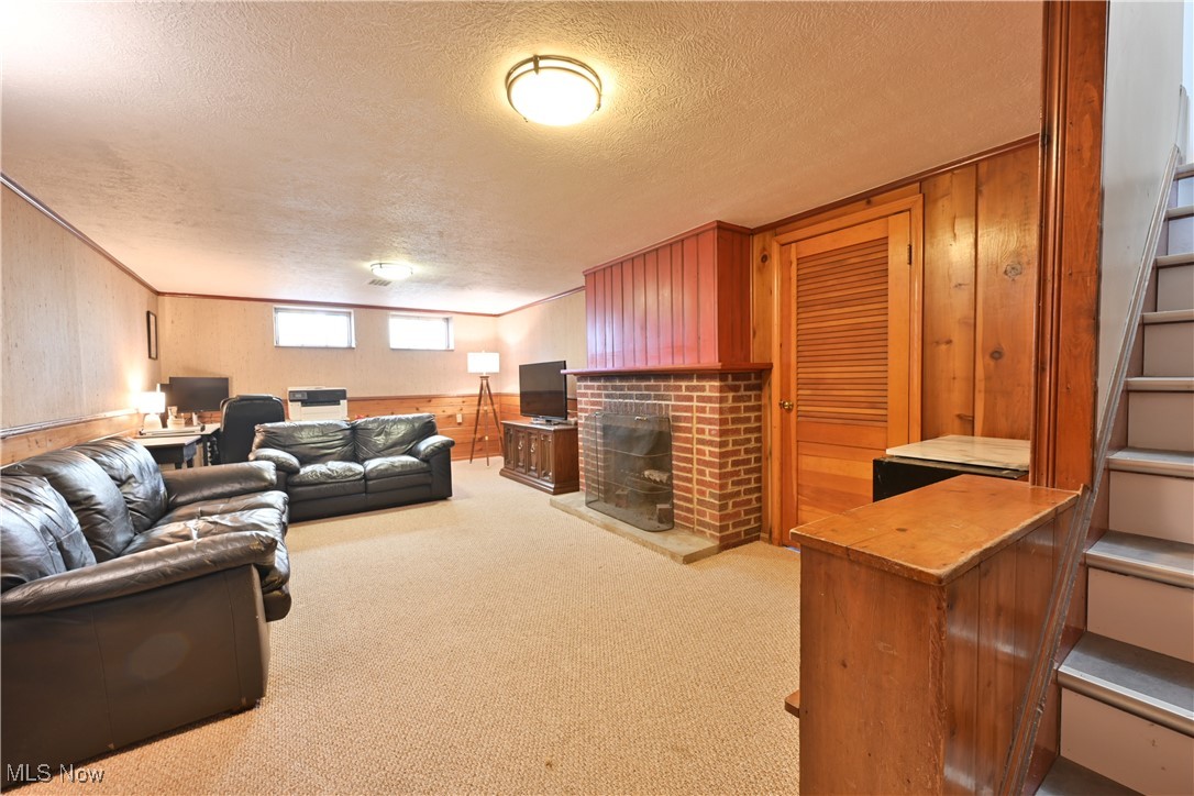 21887 Eaton Road Cleveland, OH 44126 - Photo 28 of 34 Living room featuring light colored carpet, a fireplace, a textured ceiling, stairs, and wooden walls