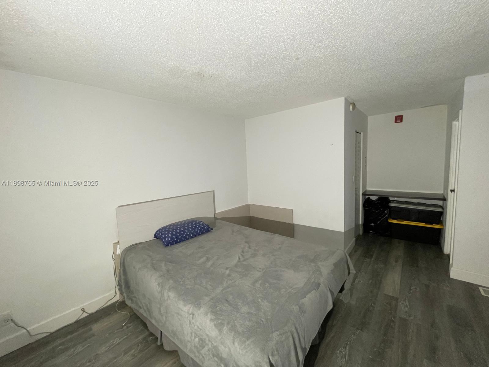 18101 Northwest 68th Avenue, Unit E201 Hialeah, FL 33015 - Photo 7 of 15 a bedroom with a bed and a cabinets