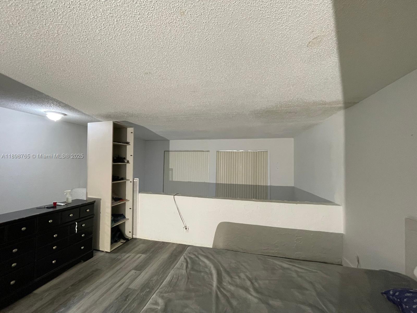 18101 Northwest 68th Avenue, Unit E201 Hialeah, FL 33015 - Photo 8 of 15 a living room with a couch and a dresser with wooden floor