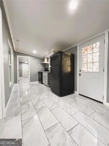 a view of a refrigerator in kitchen and an empty room