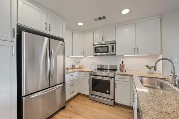 a kitchen with granite countertop a sink stainless steel appliances and cabinets
