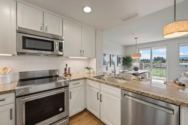 a kitchen with kitchen island granite countertop a stove a sink and dishwasher with wooden floor