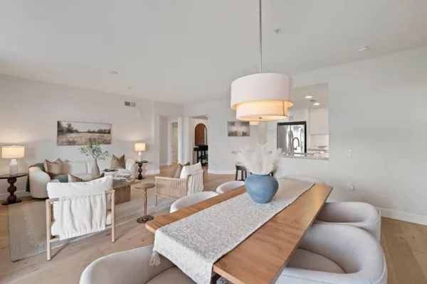a kitchen with granite countertop a sink a refrigerator a stove a dining table and chairs with wooden floor