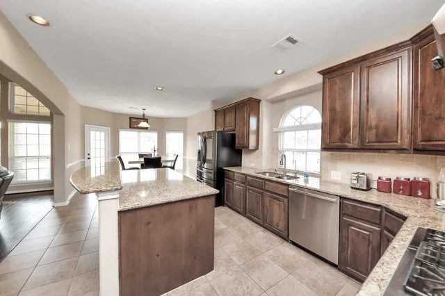 a kitchen with stainless steel appliances granite countertop a sink counter space cabinets and a large window