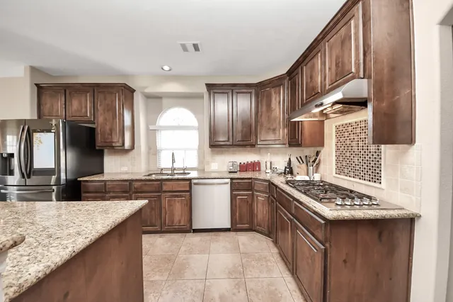 a kitchen with stainless steel appliances granite countertop a sink stove oven and refrigerator