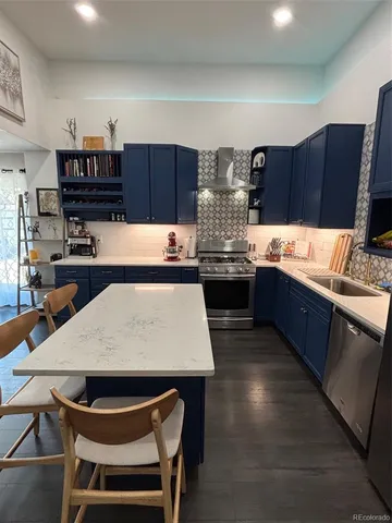 a kitchen with stainless steel appliances kitchen island granite countertop a table chairs in it and wooden floors