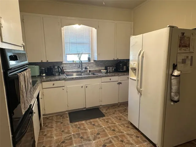 a kitchen with a refrigerator sink and cabinets