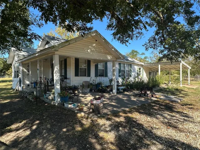 a view of a house with backyard fire pit and a large tree