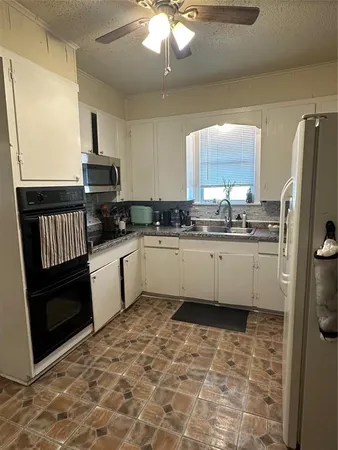 a kitchen with a sink a refrigerator and cabinets