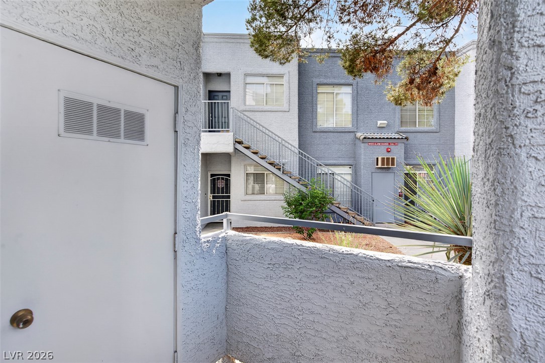 2201 Ramsgate Drive, Unit 1011 Henderson, NV 89074 - Photo 30 of 40 A striking gray and white facade with an exterior staircase leads to multiple units, amidst vibrant desert plantings.