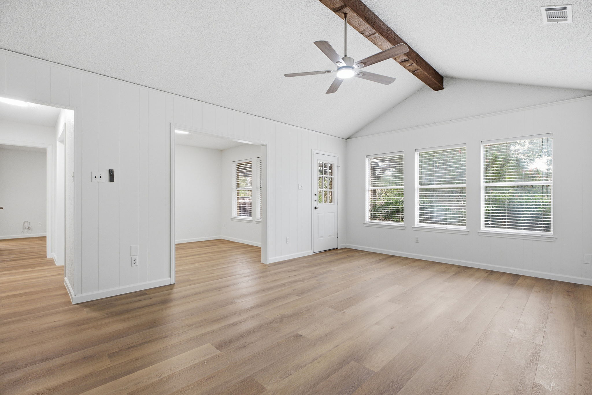 Vast, naturally illuminated living area featuring vaulted ceilings and durable wood flooring.