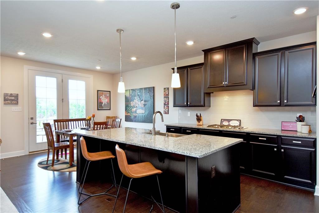 4103 Spruce Road Gibsonia, PA 15044 - Photo 5 of 25 a kitchen with stainless steel appliances granite countertop a sink a stove a refrigerator a dining table and chairs with wooden floor