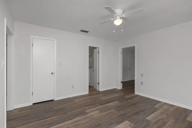 an empty room with wooden floor and ceiling fan