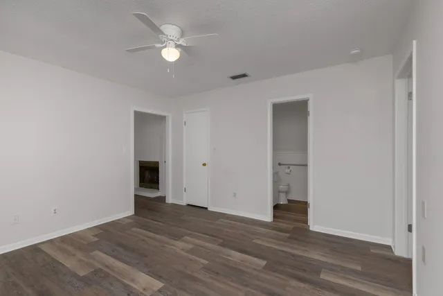 a view of an empty room with wooden floor and a ceiling fan