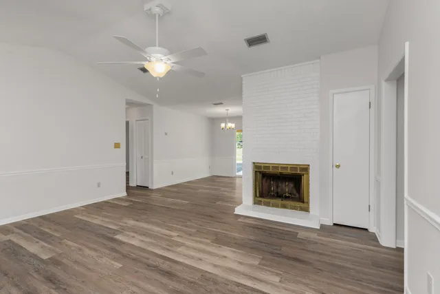 a view of an empty room with wooden floor fireplace and a window