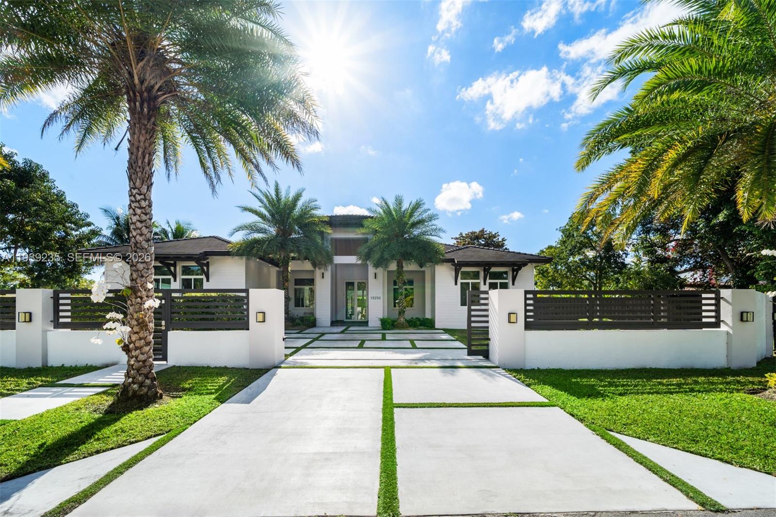 a view of a house with a yard and palm trees