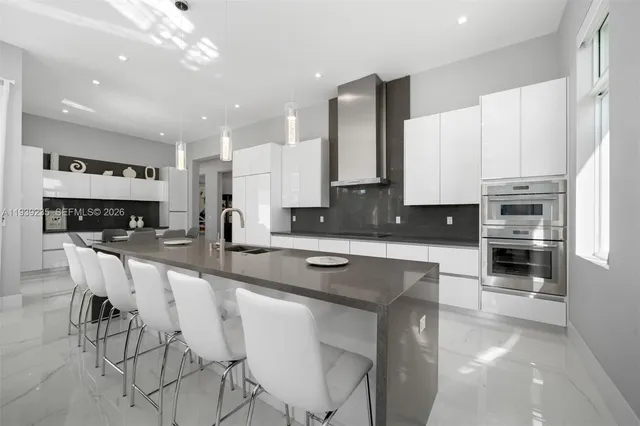 a large white kitchen with stainless steel appliances and a sink