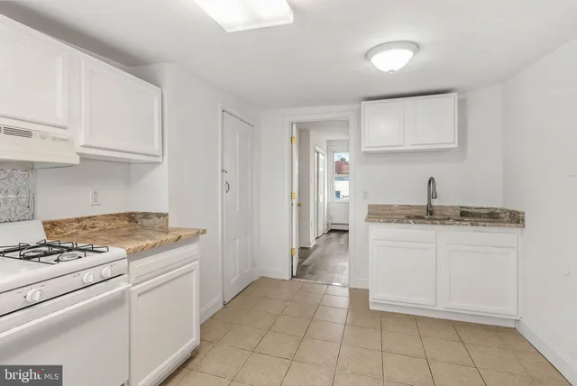 a kitchen with granite countertop a sink stove and cabinets