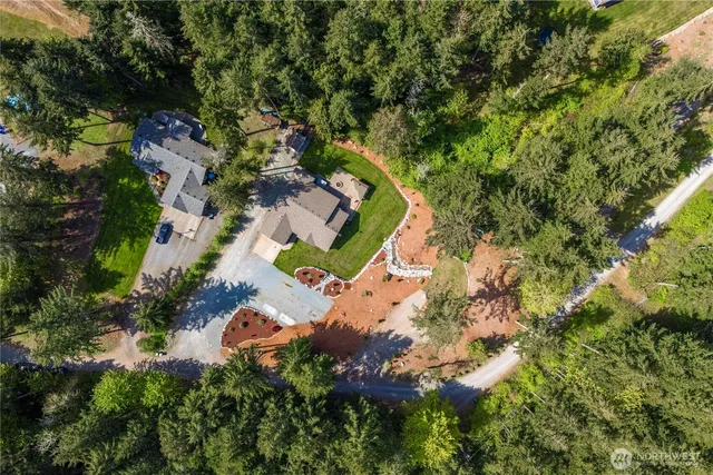 an aerial view of residential house with outdoor space and trees all around