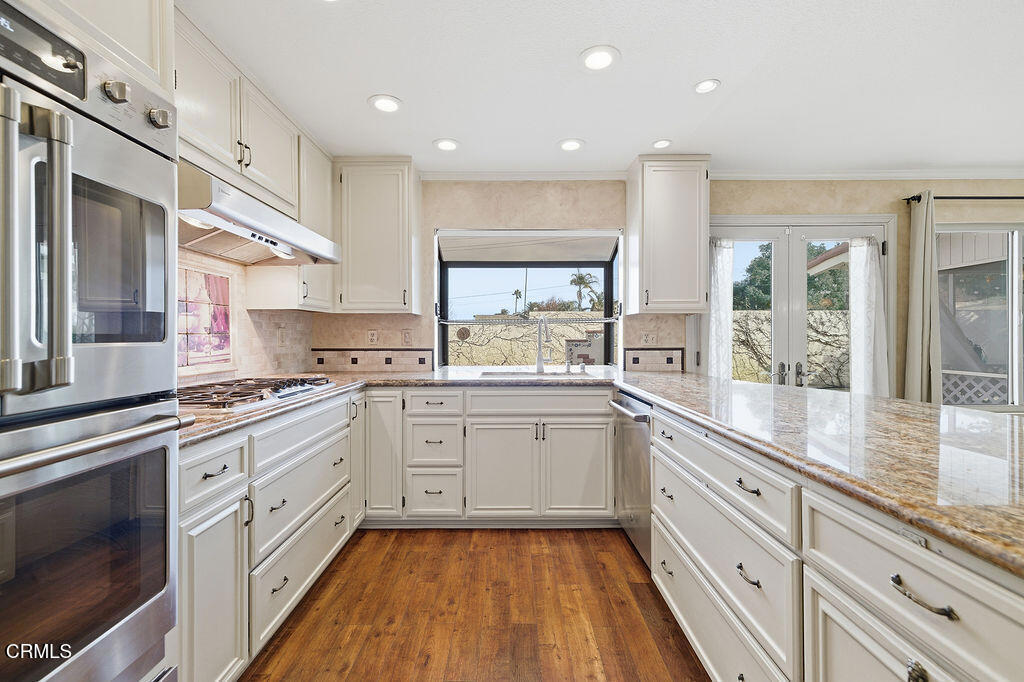 4024 Cliffrose Avenue Moorpark, CA 93021 - Photo 15 of 40 a large kitchen with stainless steel appliances granite countertop a stove a sink and white cabinets
