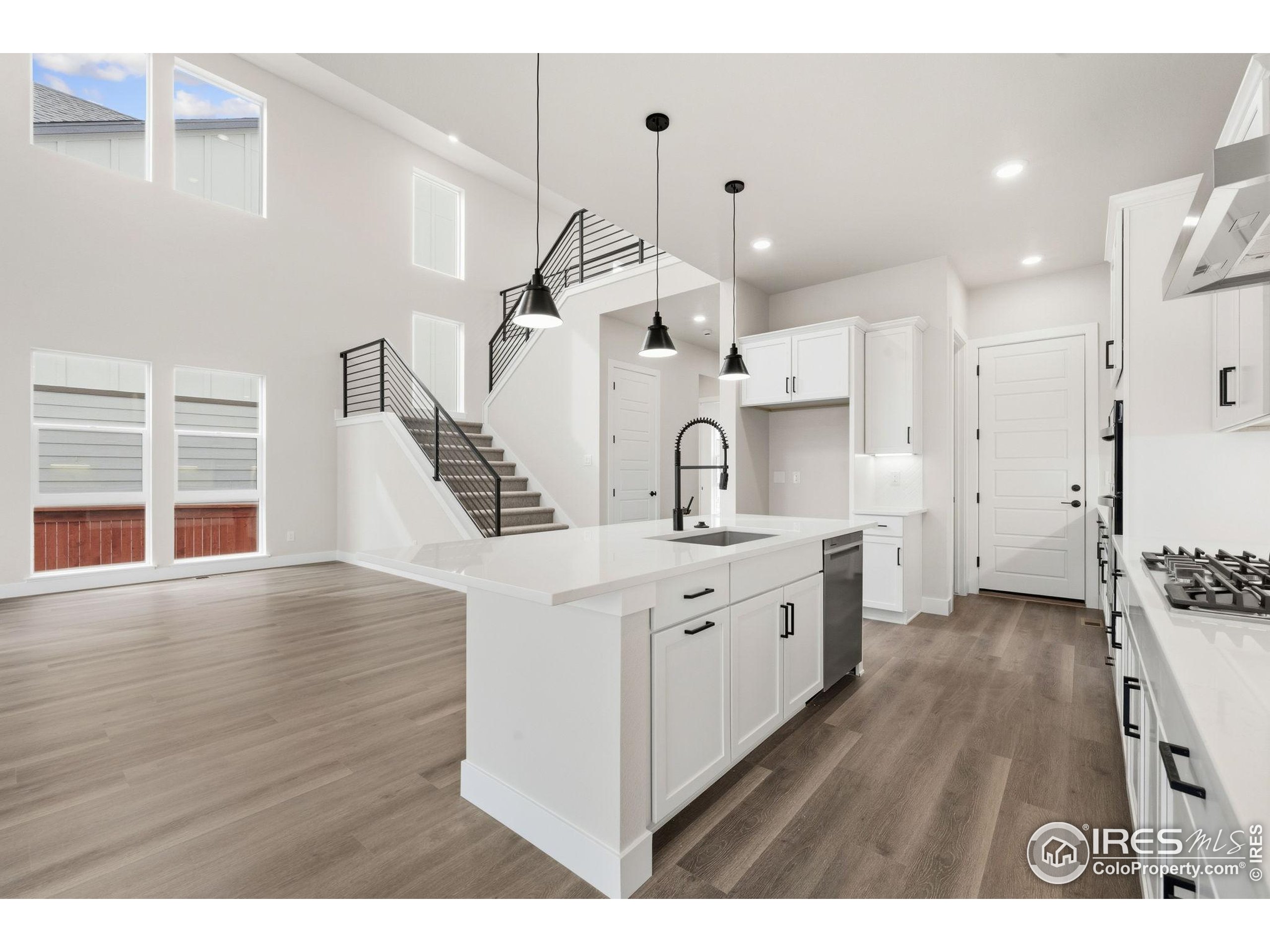 a large white kitchen with kitchen island a stove a sink dishwasher and wooden cabinets with wooden floor