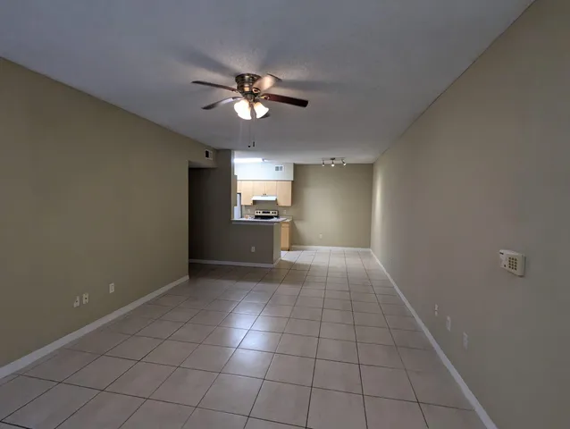 a view of an empty room with a chandelier fan and windows