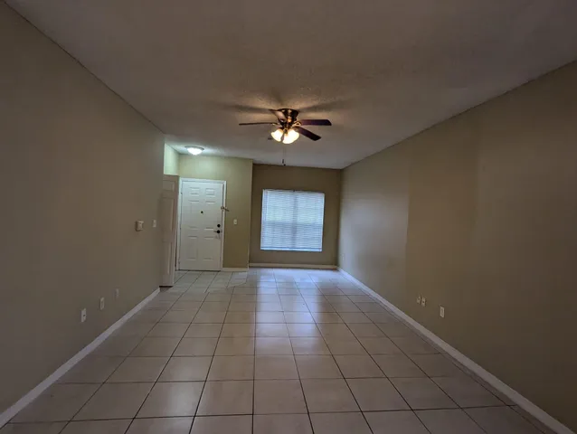 an empty room with chandelier fan and windows