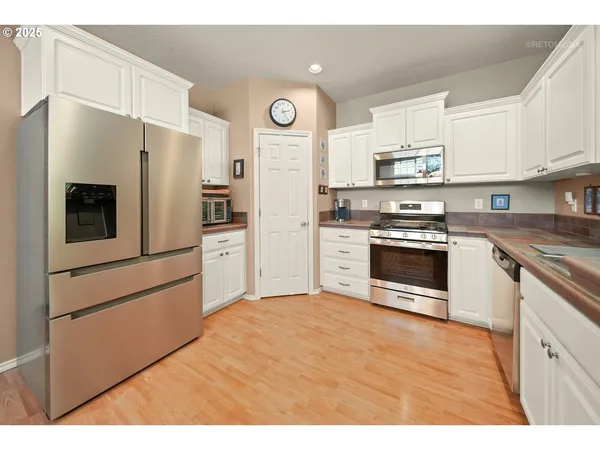 a kitchen with stainless steel appliances a refrigerator stove and white cabinets
