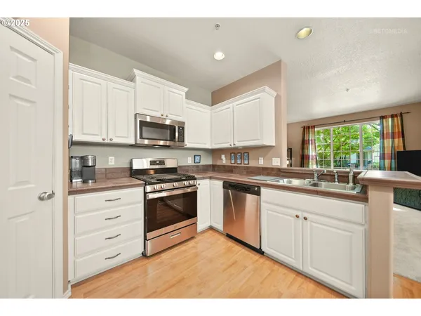 a kitchen with granite countertop white cabinets and stainless steel appliances