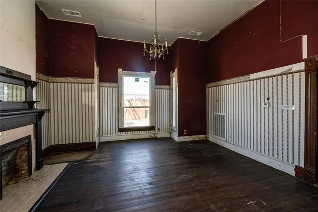 an empty room with wooden floor fireplace and windows
