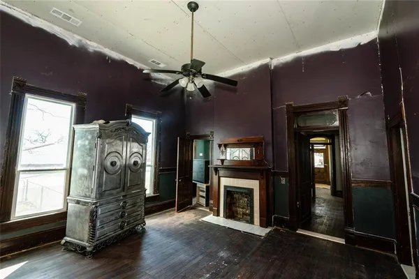 a view of a livingroom with a fireplace a ceiling fan and windows