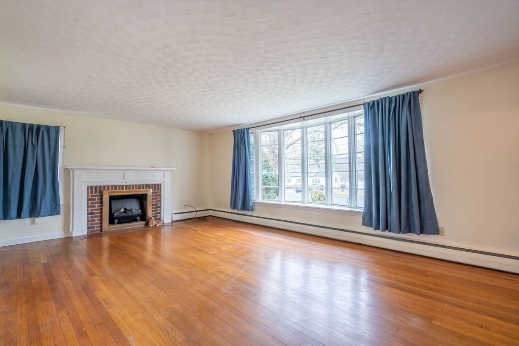 838 Pleasant Street Rochdale, MA 01542 - Photo 9 of 30 a view of an empty room with wooden floor fireplace and a window