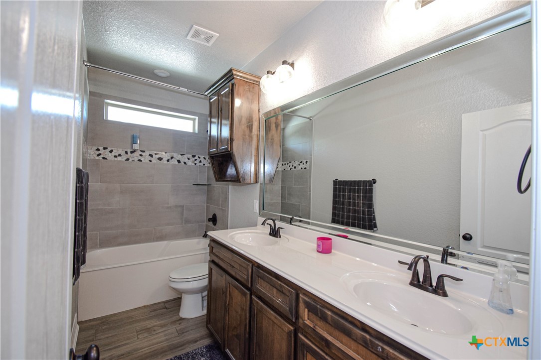 7623 Palladium Loop Killeen, TX 76542 - Photo 24 of 48 a bathroom with a double vanity sink toilet mirror and shower