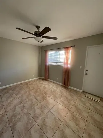 a view of an empty room and window and ceiling fan