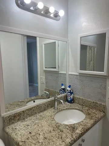 a bathroom with a granite countertop sink and a mirror