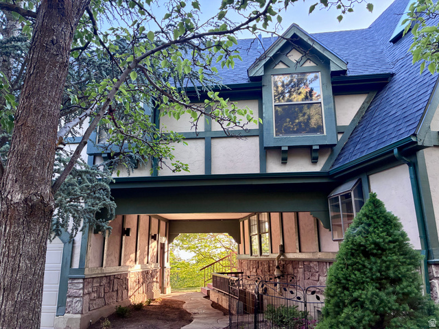 1903 Ridgehollow Drive Bountiful, UT 84010 - Photo 21 of 24 Tudor-style exterior showcasing a prominent dormer window, dark blue shingle roof, stone foundation accents, and a distinctive covered entryway