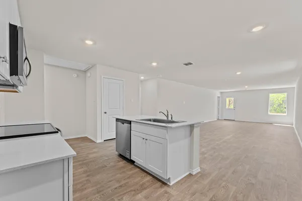 a view of a kitchen with a sink and dishwasher with wooden floor