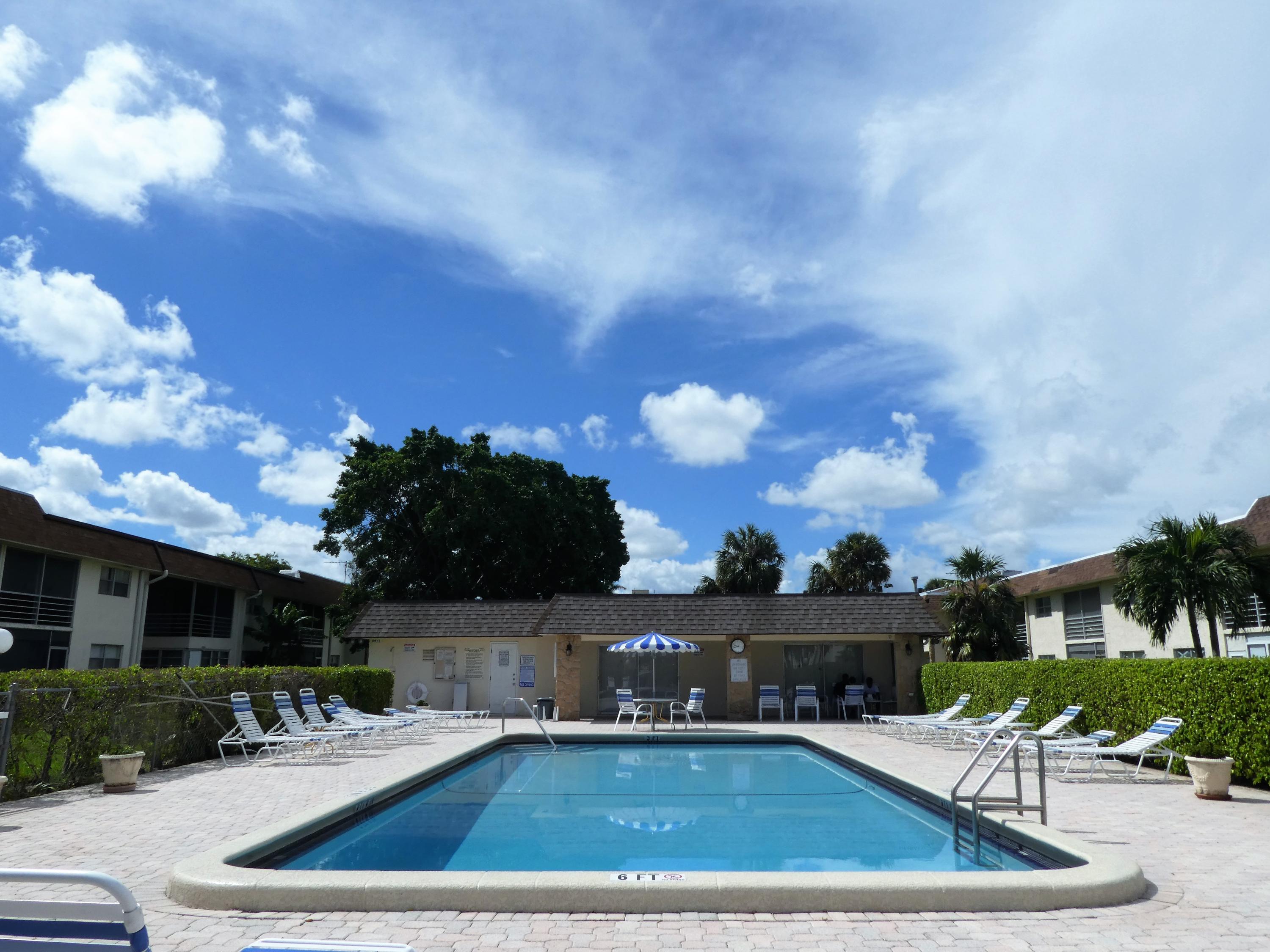 9855 Sandalfoot Boulevard, Unit 306 Boca Raton, FL 33428 - Photo 16 of 25 a view of a swimming pool with lawn chairs and a fire pit
