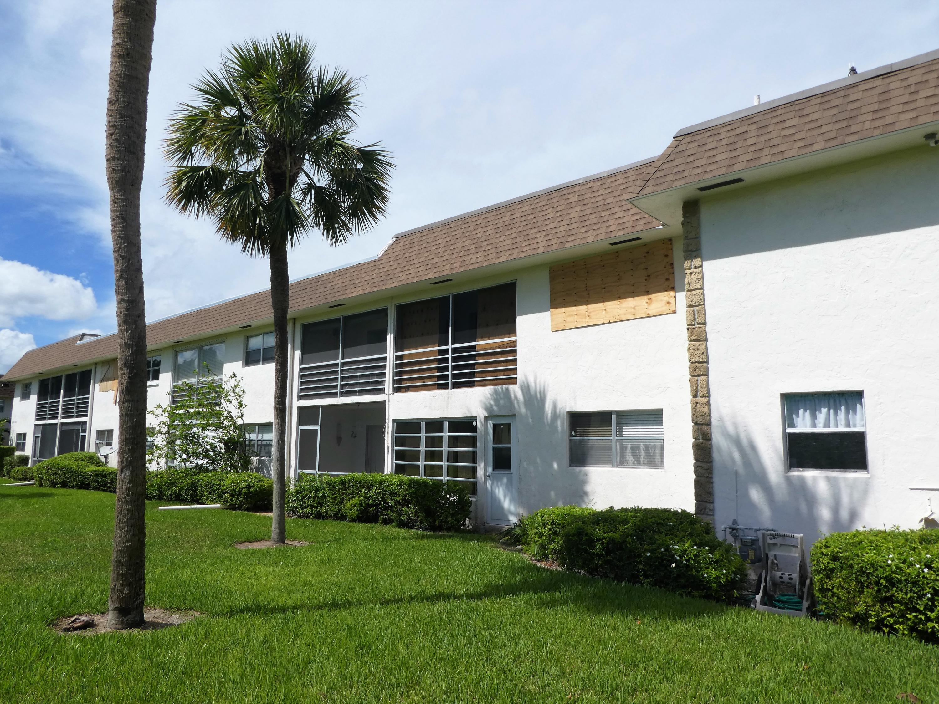 9855 Sandalfoot Boulevard, Unit 306 Boca Raton, FL 33428 - Photo 19 of 25 a front view of a house with a yard and potted plants