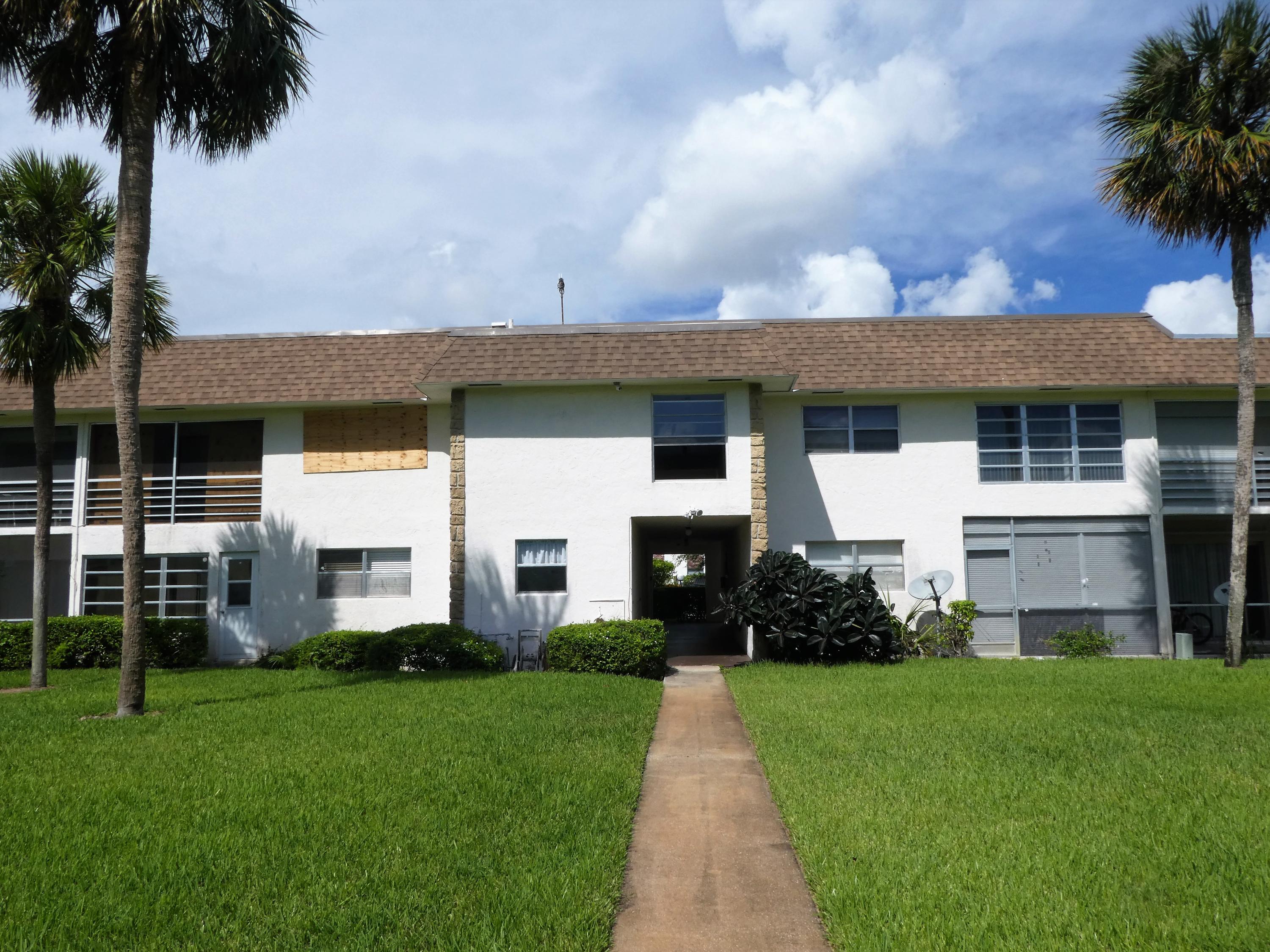 9855 Sandalfoot Boulevard, Unit 306 Boca Raton, FL 33428 - Photo 20 of 25 a front view of a house with a garden and yard