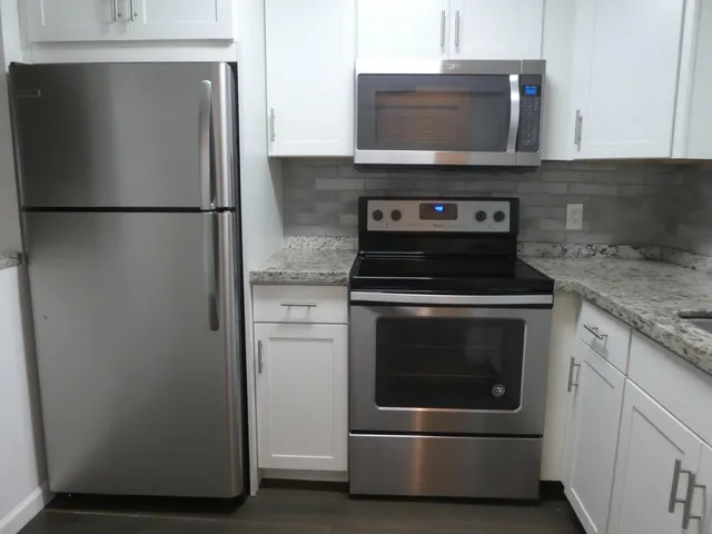 a kitchen with stainless steel appliances granite countertop a stove and a refrigerator with wooden floor