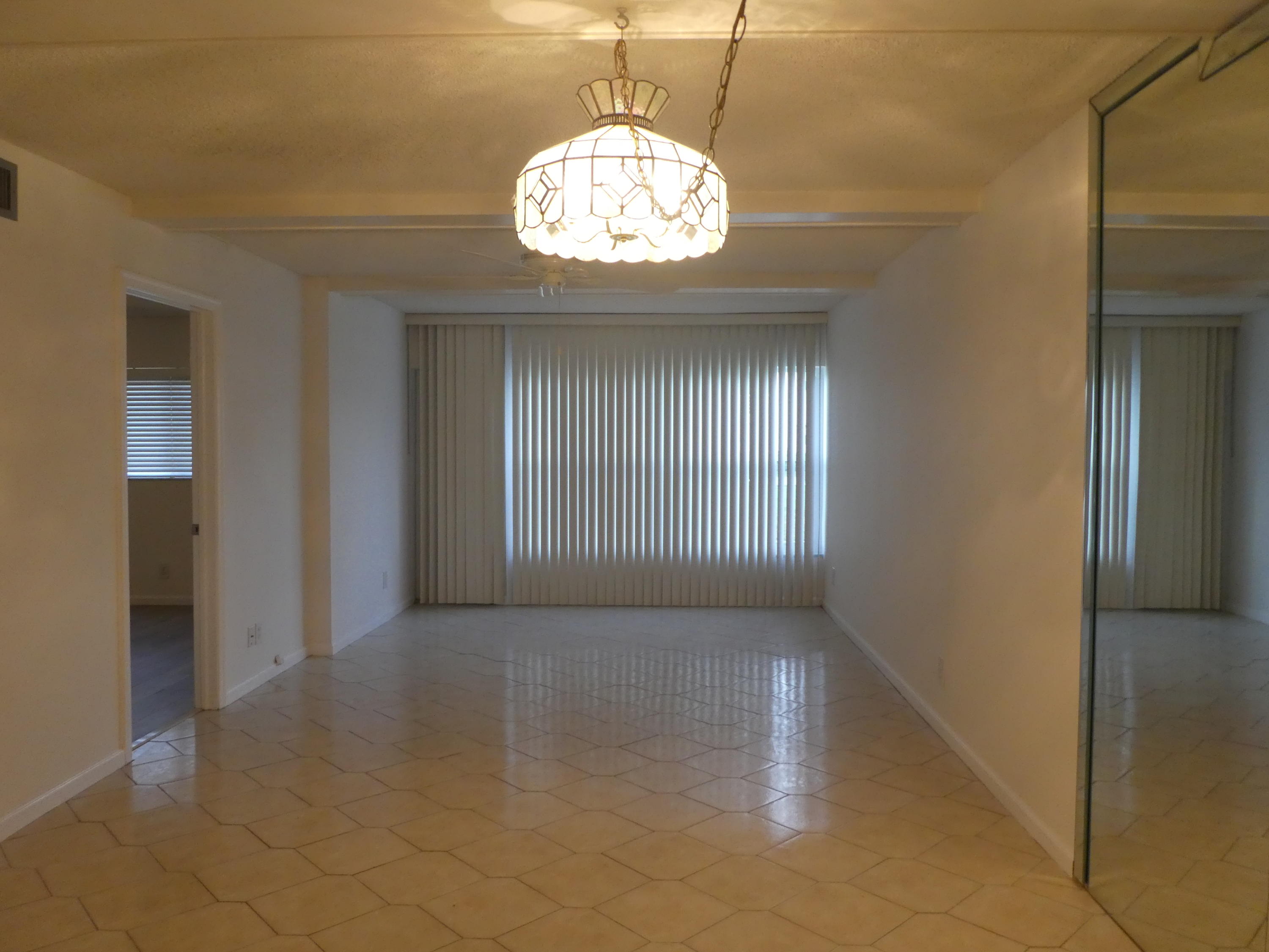 9855 Sandalfoot Boulevard, Unit 306 Boca Raton, FL 33428 - Photo 5 of 25 an empty room with wooden floor and windows