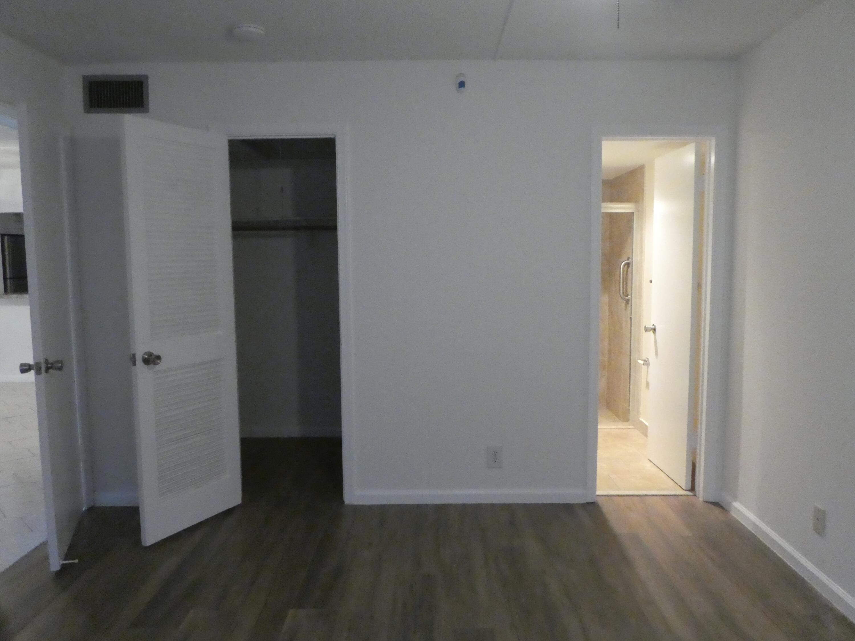 9855 Sandalfoot Boulevard, Unit 306 Boca Raton, FL 33428 - Photo 7 of 25 a view of an empty room with wooden floor and a window