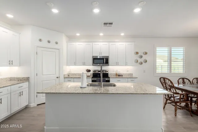 a large kitchen with stainless steel appliances granite countertop a lot of counter space and wooden floor